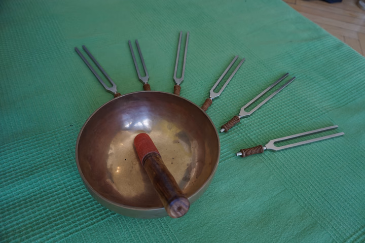 Klangschale und geeichte Stimmgabeln auf einer grünen Matte liegend zur Klangtherapie.
